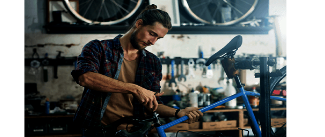 Man standing in workshop fixing bicycle